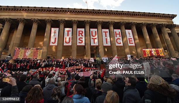 People hold Liverpool football scarves in the air as they sing "You'll Never Walk Alone" outside St George's Hall in Liverpool, north west England on...