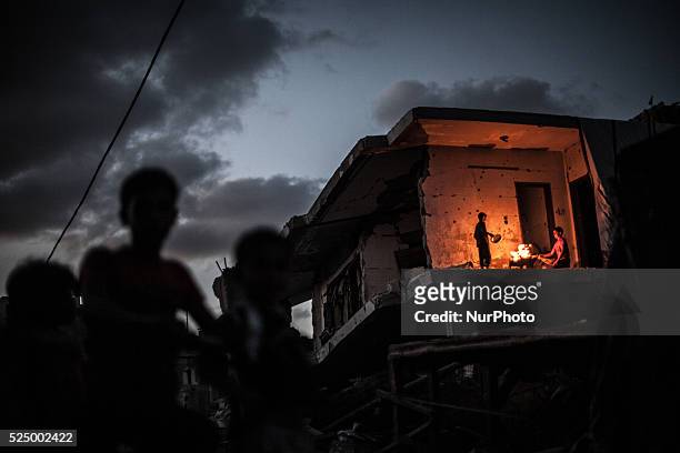 Palestinian boys stand near a fire in their home destroyed during the 50-day conflict between Hamas militants and Israel, in Shejaiya neighbourhood...