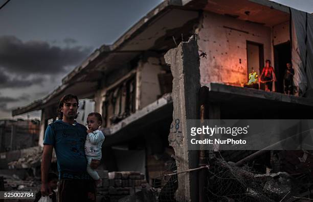 Palestinian boys stand near a fire in their home destroyed during the 50-day conflict between Hamas militants and Israel, in Shejaiya neighbourhood...