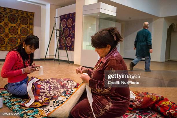 Museum workers line suzani, traditional Uzbek embroidery textile, for exhibition in new building of Samarkand State Memorial Museum, Samarkand,...