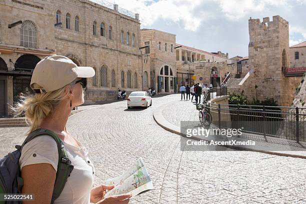 woman looks at tourist map on city street - israel travel stock pictures, royalty-free photos & images