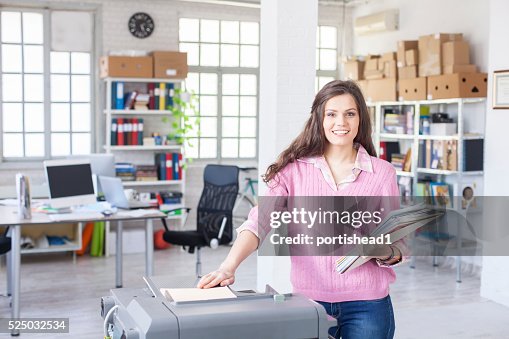 Smiling young assistant using copy machine at work Smiling young assistant using copy machine at work