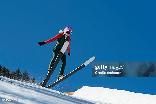 jovem atleta de salto de esqui landing contra o céu azul - ski jumping - fotografias e filmes do acervo