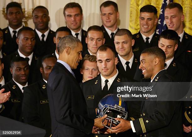 President Barack Obama is given a helmet during the Commander-in-Chief trophy presentation to the United States Naval Academy football team in the...