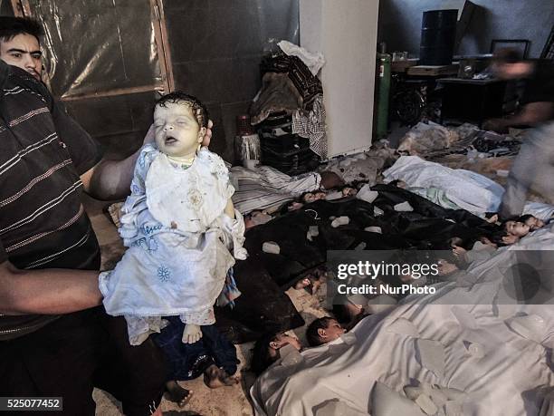 Deceased baby is held in front of a morgue filled with children after that about 1.300 people were killed by nerve gas on the Damascus suburb of...