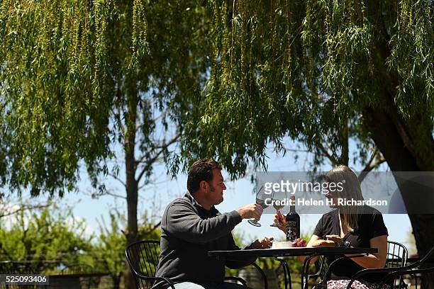Winery owner John Barbier, left, enjoys a glass of red wine with friend Christine Feller, right, on the outdoor patio at Maison La Belle Vie winery...