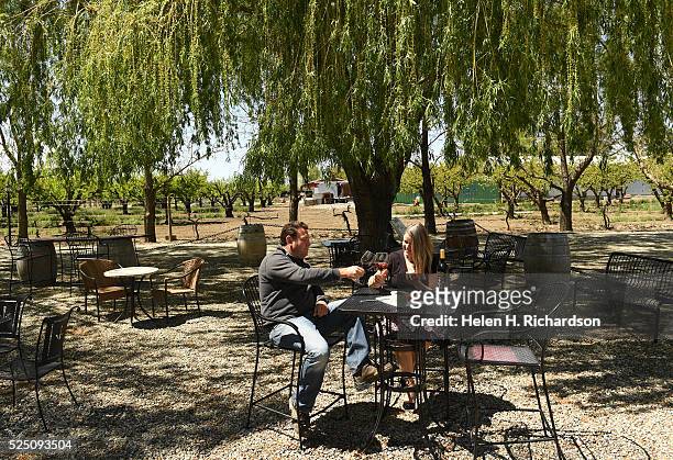 Winery owner John Barbier, left, enjoys a glass of red wine with friend Christine Feller, right, on the outdoor patio at Maison La Belle Vie winery...