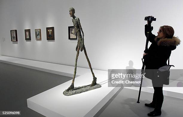 Visitor takes a picture of a sculpture Walking Man of Alberto Giacometti as part of the opening of the exhibition "Keys to a Passion" at the Louis...