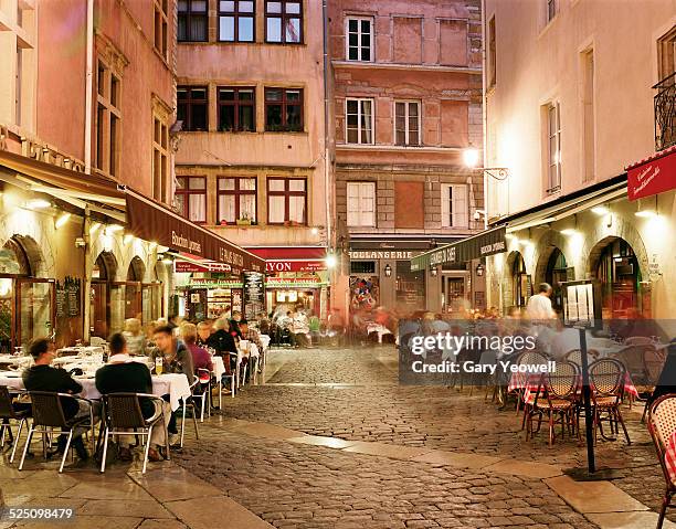 lyon, people dining along cobbled street at night - lyon france stock pictures, royalty-free photos & images