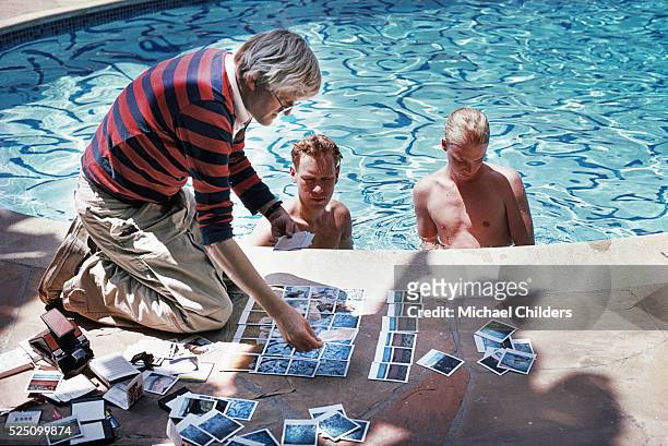 British painter, draughtsman, printmaker, stage designer and photographer David Hockney, poolside in Los Angeles, with polaroids of David Stoltz &...