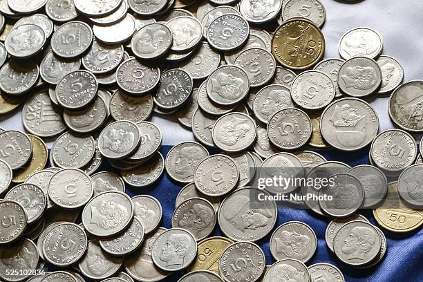 Several coins of old Drachmas on a Greek national flag.