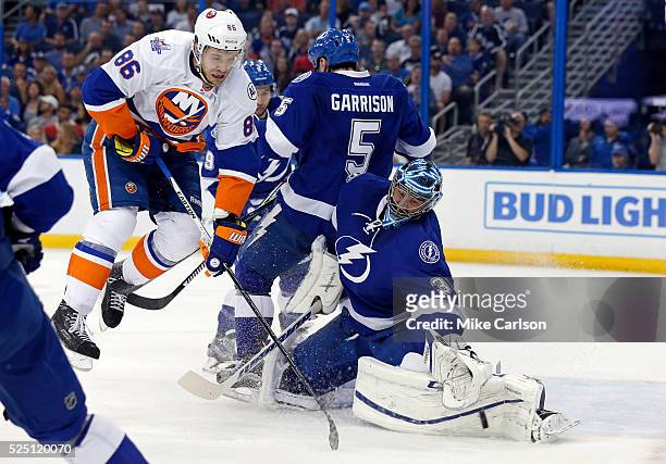 Ben Bishop of the Tampa Bay Lightning makes a save as Nikolay Kulemin of the New York Islanders crashes into Jason Garrison during the first period...