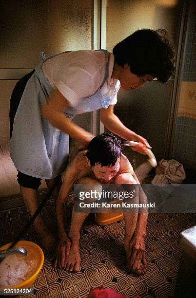 Machie Takenata, a 47 year old woman in Fukui Prefecture, bathes her invalid 73 year old mother-in-law. The son rarely is involved with the care of...