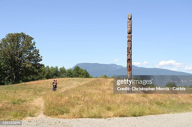 Man and child walk past a totem pole wood carving on display outside the the University of British Columbia's museum of Anthropology, designed by...