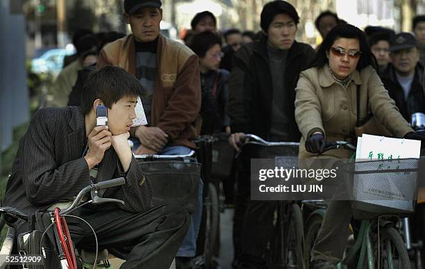 Young man uses his mobile phone while he waits for the traffic lights in Shanghai, 31 March 2005. China's largest telecoms firm, China Telecom,...