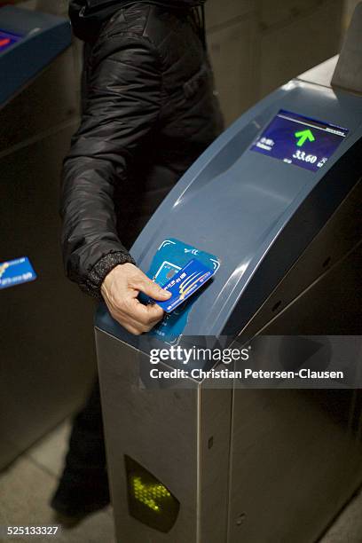 Man is entering a Beijing subway station by holding a contactless payment card over a reader. The display shows his remaining balance in RMB.