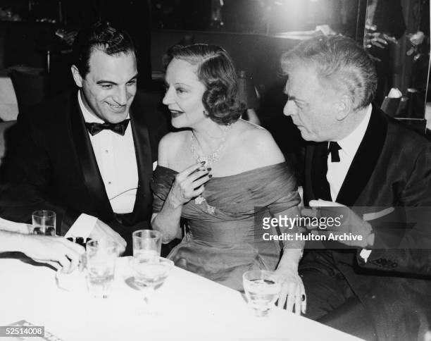 American actress Tallulah Bankhead , club owner Gerry Purcell , and film director Morton da Costa sit, talk, and smoke at a table at Purcell's Le...