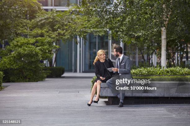 two coworkers discussing plans in a digital tablet - business park uk fotografías e imágenes de stock