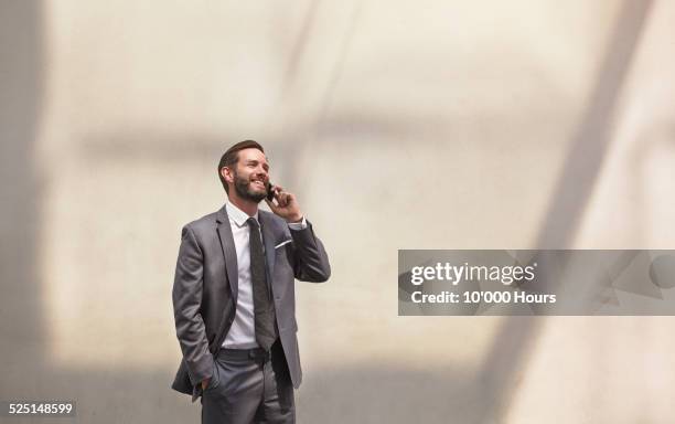 businessman using a smartphone and smiling - portrait beige background stock pictures, royalty-free photos & images