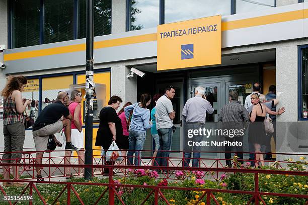 People wait in line at an ATM outside a Piraeus bank branch in a neighborhood at Dafni saburb of Athens after the announcement, during the night, by...