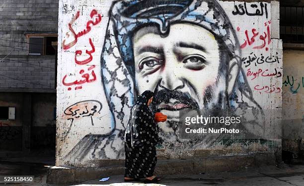 Palestinian woman walks in front of the mural of the late Palestinian leader Yasser Arafat.Salutes the Palestinians the ninth anniversary of the...