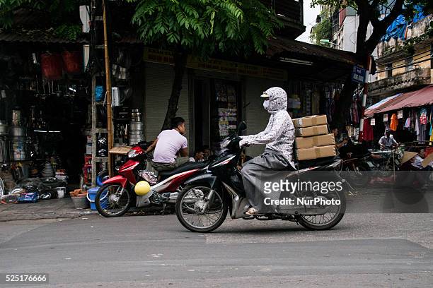 Woman is riding a bike in Hanoi, July the 5th, 2015. She is wearing specific clothes most Vietnamese women wear to avoid the sun completely. After...