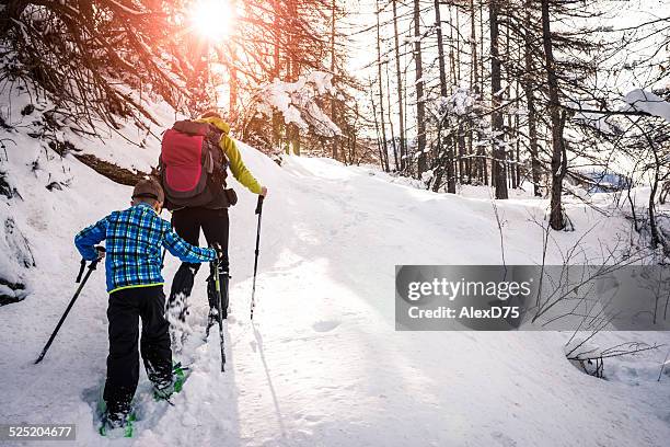 mother and son snowshoeing - sneeuwschoen stockfoto's en -beelden