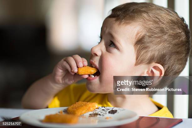 three year old eating fish - fish fingers stockfoto's en -beelden