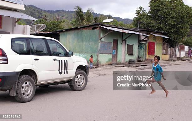 Young Timorese boy run towards a UN vehicle with a toy gun.