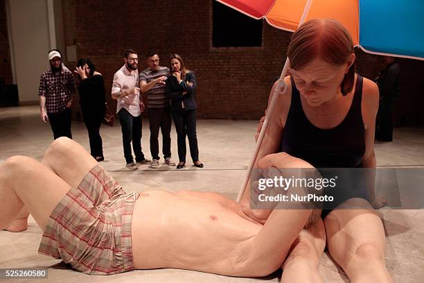 Visitors look at the sculpture entitled &quot;Couple Under Umbrella&quot; by the Australian artist Ron Mueck during his exhibition at the Pinacoteca...