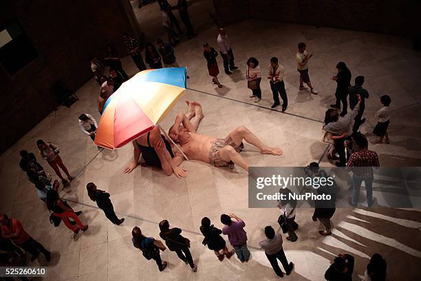 Visitors surround the sculpture entitled &quot;Couple Under Umbrella&quot; by the Australian artist Ron Mueck during his exhibition at the Pinacoteca...
