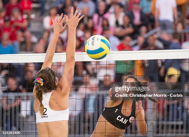 Melissa Humana-Paredes of Canada spikes the ball past Fabian Gomez of Uruguay during the the preliminary rounds of beach volleyball competition at...