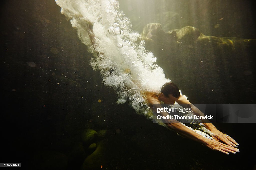 Man diving into river underwater view