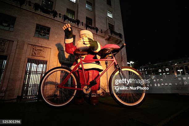Feet statue of Santa Claus with cyclist gloves and a bicycle that was placed as Christmas decoration is illuminated in front of the City Hall of Sao...