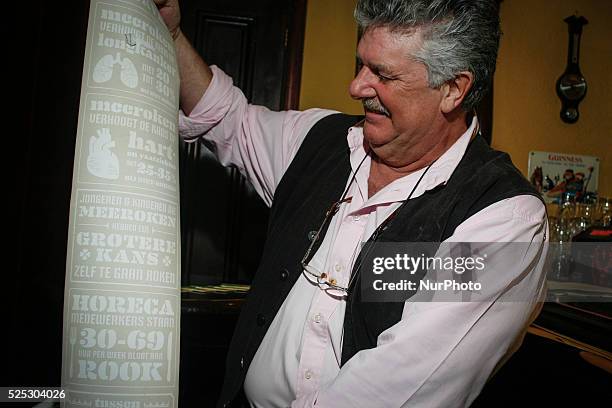 Proprietor of the oldest pub in The Hague Bart van Dam shows a paper rol with statistics printed on it informing on the harmful effects of smoking...