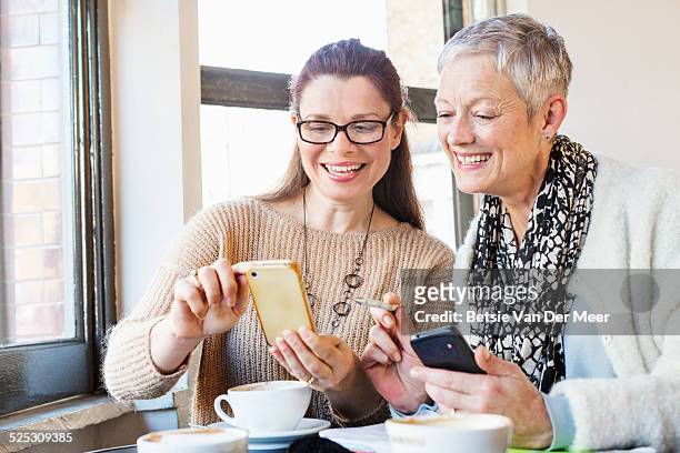 senior women comparing diaries in cafe. - phone comparison stock pictures, royalty-free photos & images