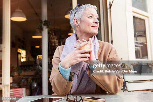 senior woman having a coffee outside in cafe. - older woman short hair stock pictures, royalty-free photos & images