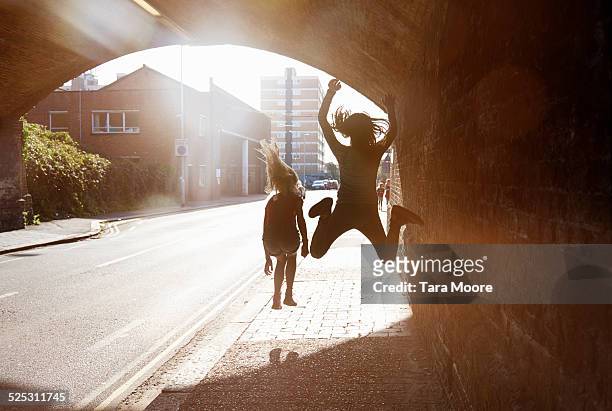 2 children jumping for joy in tunnel - jumping for joy stockfoto's en -beelden