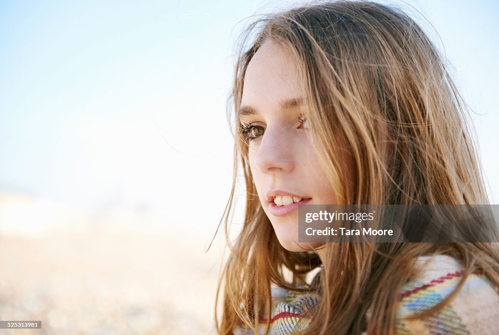 Teenage girl wrapped in blanket by seaside