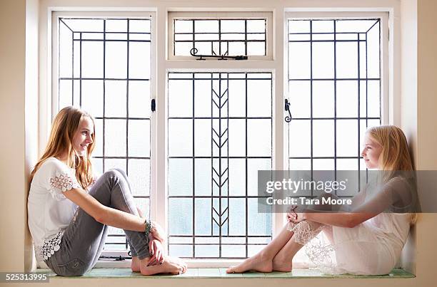 sisters looking at each other - girls barefoot in jeans fotografías e imágenes de stock