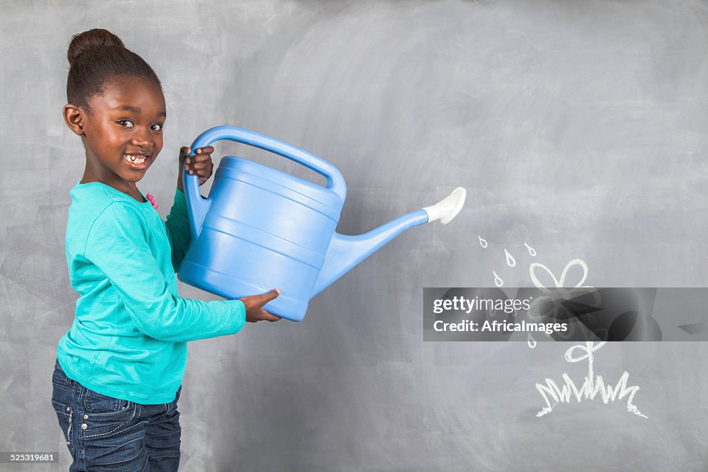 Niña a su planta riego de que deriva en una pizarra