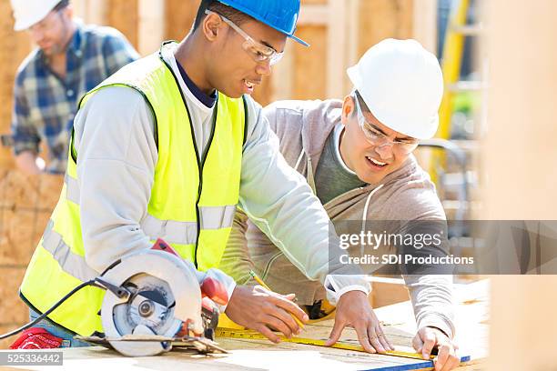 construction workers measure board at job site - saw blade stock pictures, royalty-free photos & images