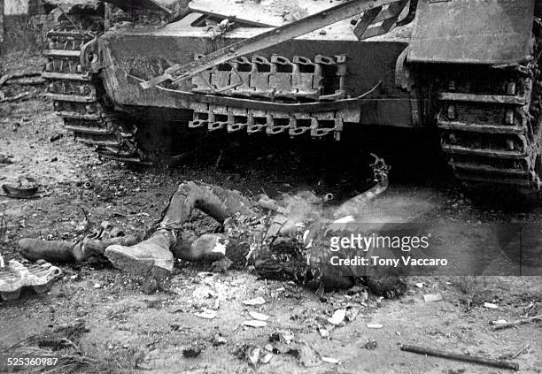 The still-burning corpse of a soldier can be seen in front of a tank near Hemmerden, Germany during the Allied push to the Rhine, World War II. The...