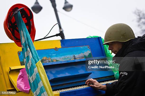 An activist of anti-government opposition wearing military helmet plays apiano set on the barricade in Kiev during a concert organized for the...