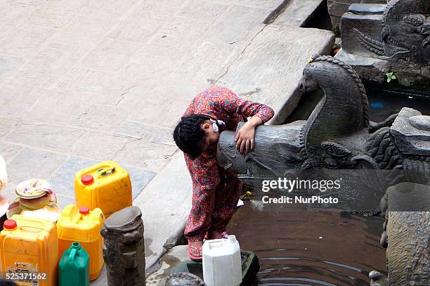 Girl check in the traditional stone tap as she waits for water to fill her water tank in in Patan near Kathmandu, Nepal, March 22, 2015. World Water...