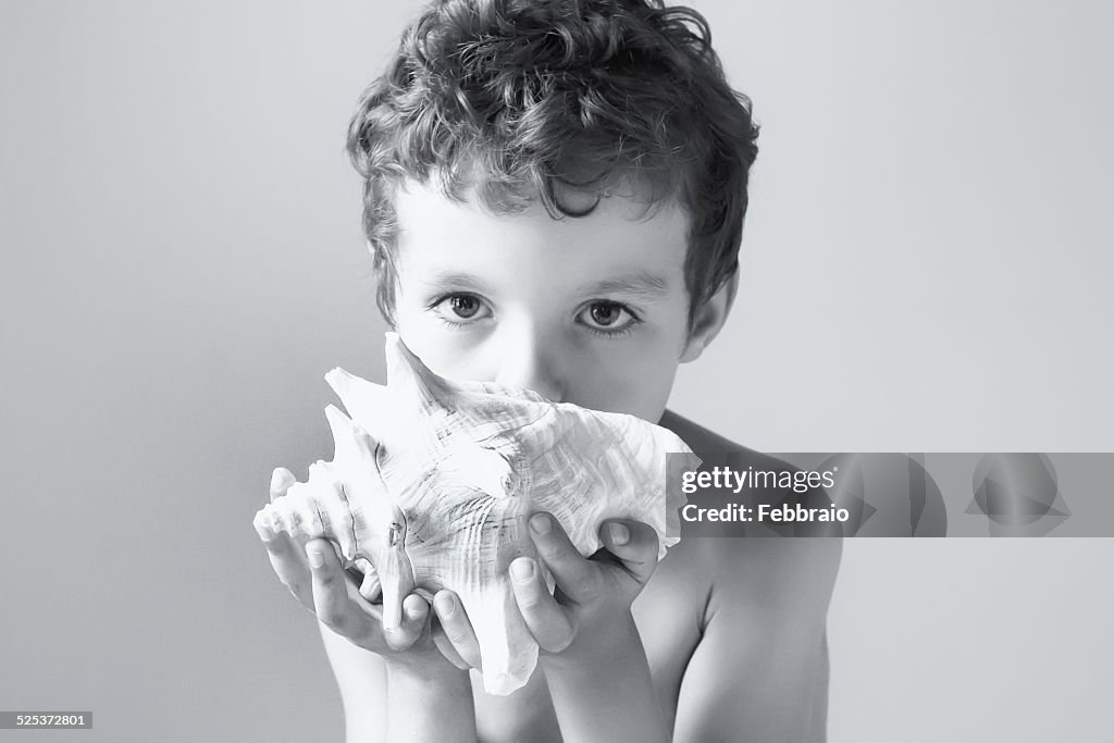 Portrait of child blowing a conch shell
