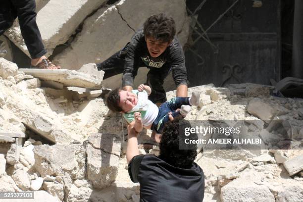 Syrians evacuate a toddler from a destroyed building following a reported air strike on the rebel-held neighbourhood of al-Kalasa in the northern...