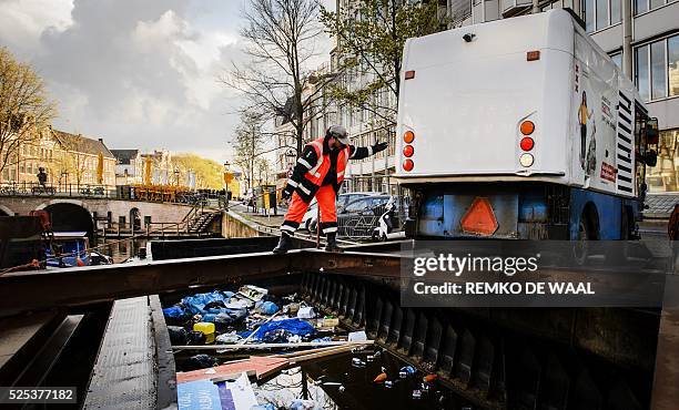 Cleaning teams pile waste in a large bulk barge on the Singel in Amsterdam on April 28 the day after the nation celebrated King's Day or Koningsdag,...
