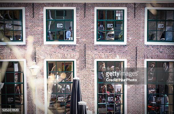 People can be seen at work in the library of Leiden on April 15, 2015 while beneath reflected in the windows people are seen enjoying the sun on a...