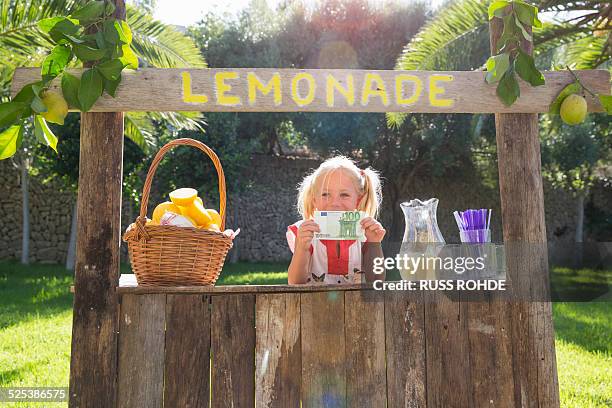 portrait of girl on lemonade stand holding up one hundred euro note - kids money fotografías e imágenes de stock